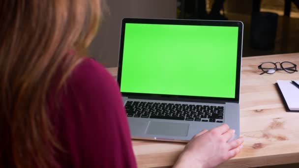 Задній портрет бізнес-леді, що має відеозапис на ноутбуці з зеленими хромованими хвилями екрану вручну в ньому в офісі . — стокове відео