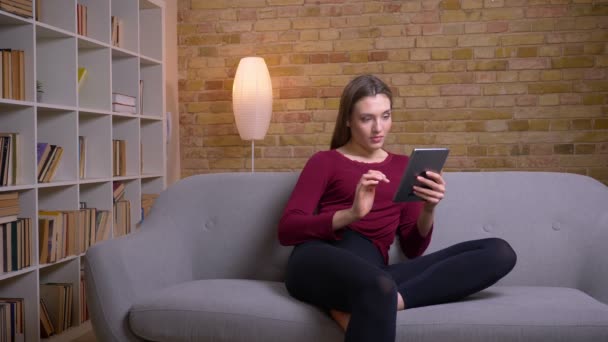 Giovane e bella bruna freelance che lavora con tablet concentrandosi a casa . — Video Stock