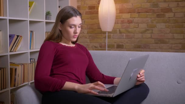 Young and beautiful brunette female freelancer working with laptop being concentrated at home. — Stockvideo