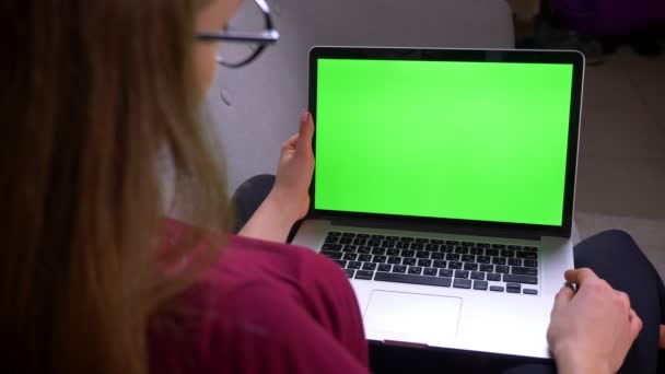 Portrait arrière de femme d'affaires dans des lunettes regardant dans un ordinateur portable avec écran chromatique vert à la maison . — Video