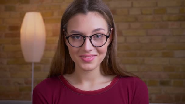 Porträtt av unga och vackra brunett kvinna i glasögon ler vackert i kameran i hemmet. — Stockvideo