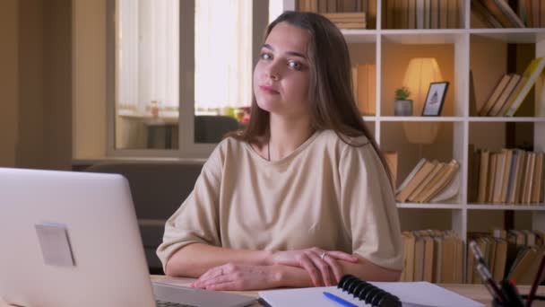 Retrato de close-up de jovem atraente mulher de negócios caucasiana olhando para a câmera e sorrindo alegremente usando o laptop dentro de casa no escritório — Vídeo de Stock