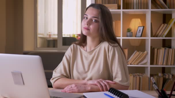 Gros plan portrait de jeune femme d'affaires caucasienne attrayante regardant la caméra et souriant joyeusement en utilisant l'ordinateur portable à l'intérieur dans le bureau — Video