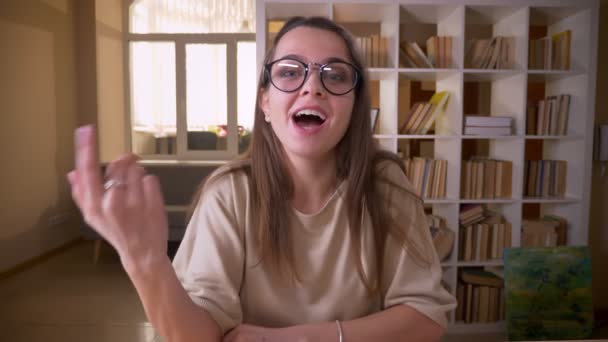 Κοντινό πλάνο του νεαρού ελκυστικό καυκάσιο θηλυκό blogger σε γυαλιά που μιλούν για streaming φωτογραφική μηχανή ζωντανά σε εσωτερικούς χώρους στο διαμέρισμα — Αρχείο Βίντεο