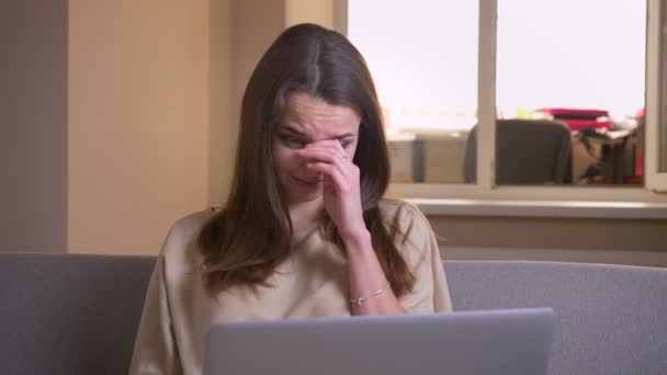 Close-up portret van jonge aantrekkelijke blanke vrouw met behulp van de laptop en het kijken naar een horrorfilm zittend op de Bank binnenshuis in het appartement — Stockvideo