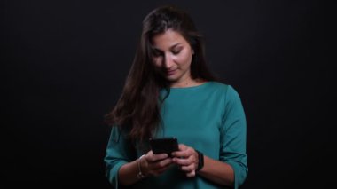 Siyah izole arka plan ile kamera bakarak telefon kullanarak genç güzel esmer kadın Closeup portre