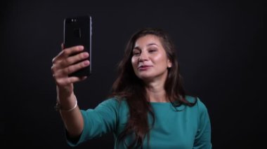 Siyah izole arka plan ile telefonda bir görüntülü arama olan genç güzel esmer kadın Closeup portre