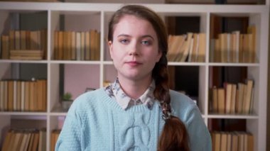 Üniversite kütüphanesinde kameraya bakan genç güzel kız öğrencinin closeup portresi