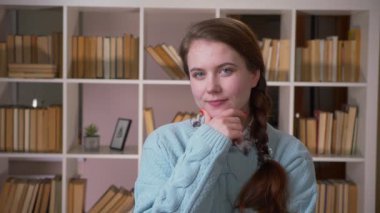 Genç güzel kız öğrenci nin kapalı alanda kameraya bakarak gülümseyerek buruna yakın çekim portresi