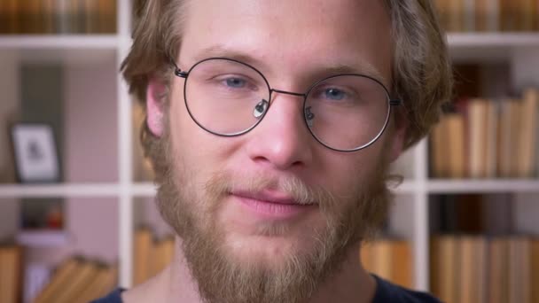 Close-up shoot van volwassen aantrekkelijke mannelijke student in glazen knikkend glimlachend vrolijk kijken naar camera in de Universiteitsbibliotheek binnenshuis — Stockvideo