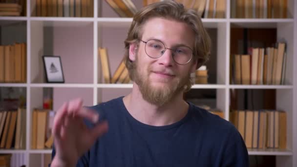Nahaufnahme eines erwachsenen attraktiven männlichen Studenten, der in der Universitätsbibliothek drinnen sein Okay gibt und in die Kamera schaut — Stockvideo