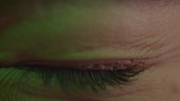 Tiro close-up de olho azul-claro piscando com reflexão da lâmpada em luz verde e piscar de olhos . — Vídeo de Stock
