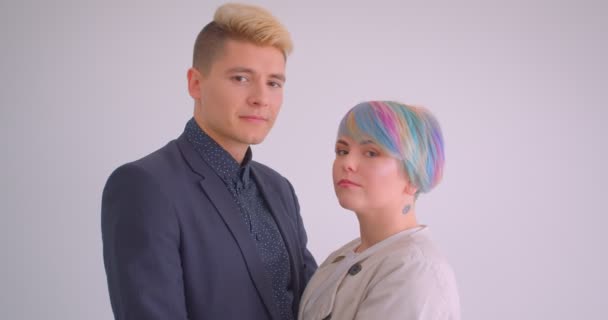 Millenial caucasian couple hugging tenderly on white background watching at each other and into camera being serious. — 비디오