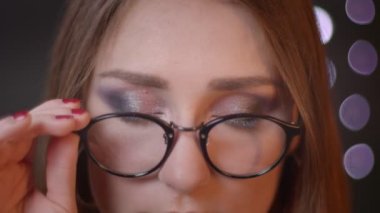 Gözlüklü genç ve beyaz beyaz kızın kameraya bakan ve bokeh arka plan ile gülümseyen closeup portre