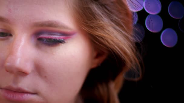 Primo piano sparare di giovane attraente viso femminile caucasico con metà applicato glitter trucco guardando la fotocamera — Video Stock