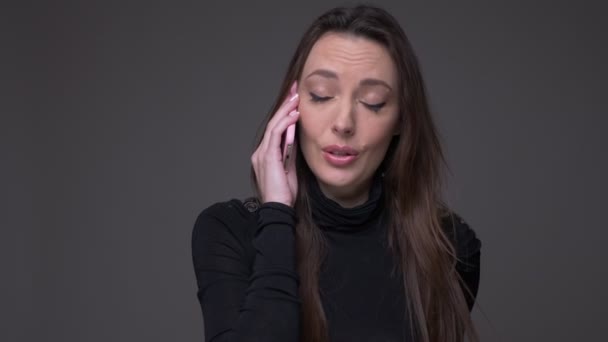 Ritratto di attraente donna bruna che parla sul cellulare essendo felice e positivo isolato su sfondo grigio . — Video Stock