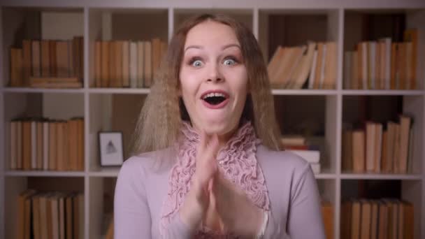 Froh kaukasischen welligen blonden Lehrer rollenden Augen äußerst amüsiert und überrascht in der Bibliothek. — Stockvideo