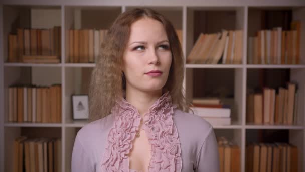 Portret van Kaukasische blonde leraar met golvende haren wordt in de bibliotheek. — Stockvideo