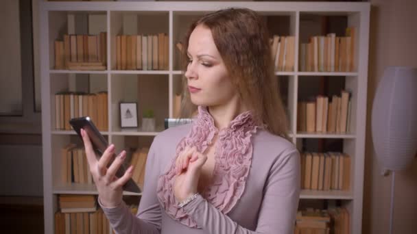 Портрет кавказької хвилястої блондинки-вчителя, що працює з планшетом, показує зелений екран хромосоми на камеру в бібліотеці . — стокове відео