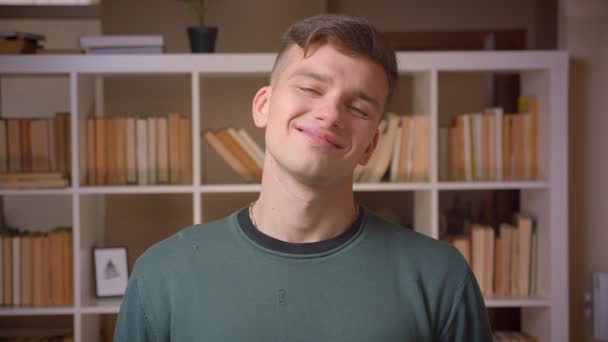 Portrét mladého mužského studenta úsměvů do kamery měnící se emoce v knihovně. — Stock video