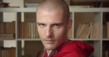 Genç çekici beyaz erkek öğrenci tornalama ve kolej Kütüphanesi kapalı kamera bakıyor portre closeup