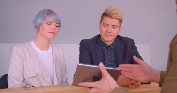 Zbliżenie strzelać młodej pięknej pary Hipster zakupu mieszkania rozmowy z Realtor z tabletu w pomieszczeniu — Wideo stockowe