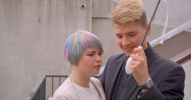 Close-up shoot van jonge mooie hipster paar staan samen onder paraplu gelukkig buitenshuis — Stockvideo