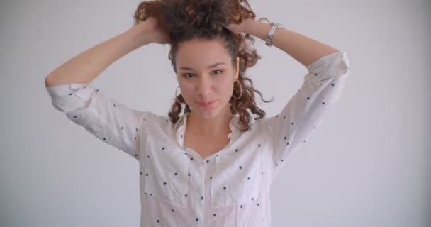 Disparo de cerca de jóvenes con estilo de pelo largo rizado caucásico hembra lanzando el pelo sonriendo felizmente mirando a la cámara con el fondo aislado en blanco — Vídeos de Stock