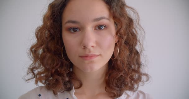 Nahaufnahme Porträt der jungen ziemlich langhaarigen lockigen kaukasischen Frau Blick auf die Kamera mit Hintergrund isoliert auf weiß — Stockvideo