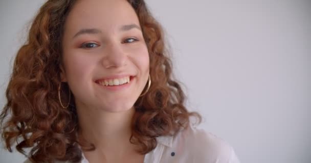 Nahaufnahme Porträt der jungen ziemlich langhaarigen lockigen kaukasischen Frau lächelt glücklich posiert vor der Kamera mit Hintergrund isoliert auf weiß — Stockvideo