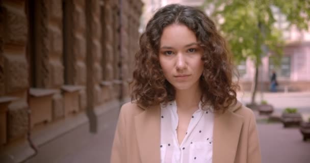 Gros plan pousse de jeune longue chevelure bouclée caucasienne étudiante souriante marchant joyeusement vers la caméra à l'extérieur dans la rue — Video