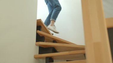 Rahat bir dairede alt katta yürüyen kot pantolon ve spor ayakkabı genç sevimli kadın bacaklar Closeup ateş