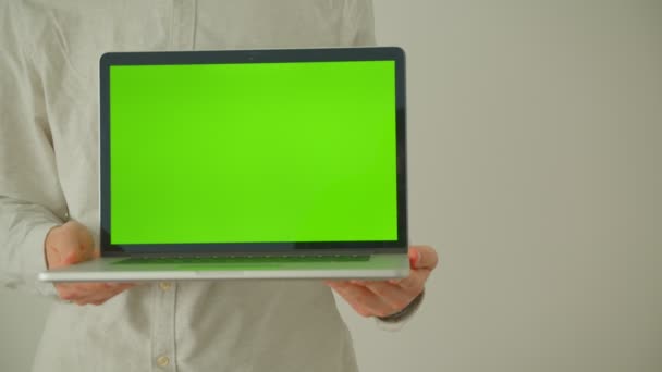 Съемка крупным планом мужских рук, держащих ноутбук с зеленым экраном в помещении офиса — стоковое видео