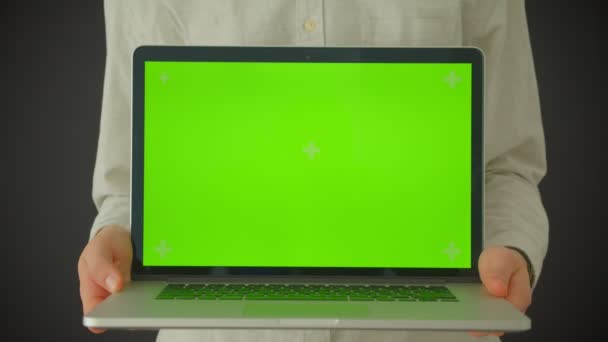 Съемка крупным планом мужских рук, держащих ноутбук с зеленым экраном в помещении с изолированным на сером фоне — стоковое видео