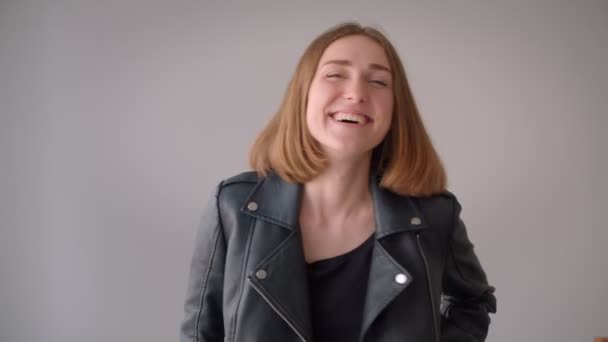 Primer plano retrato de joven linda chica caucásica sonriendo alegremente mirando a la cámara en el interior de la habitación vacía — Vídeo de stock