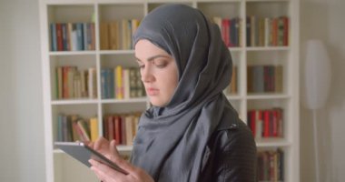 Kapitayda kapitörlü genç çekici müslüman kız öğrencinin tableti kullanarak yakın çekim portresi
