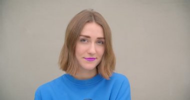 Mor ruj ile genç kısa saçlı kadın closeup portre arka planda sokak duvarı ile kamera bakarak gülümseyerek