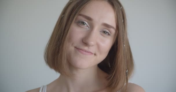 Close-up shoot van jonge mooie Kaukasische vrouw met haar ringen en glitter make-up glimlachend kijken naar de camera in de witte kamer binnenshuis — Stockvideo