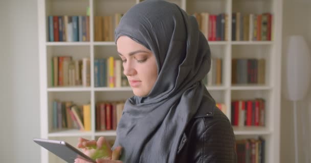 Närbild porträtt av unga attraktiva muslimska kvinnliga studenten i hijab använda tabletten visar grön Chroma skärm till kameran i kollegiet biblioteket inomhus — Stockvideo