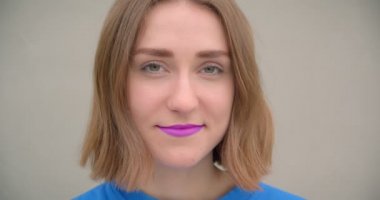 Mor ruj ile genç kısa saçlı esmer kadın Closeup portre arka planda sokak duvarı ile kamera önünde mutlu poz gülümseyen