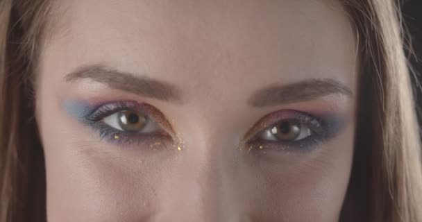 Close-up shoot van jonge mooie Kaukasische kortharige vrouwelijk gezicht met glitter make-up kijken naar camera met lachende uitdrukking met achtergrond geïsoleerd op zwart — Stockvideo