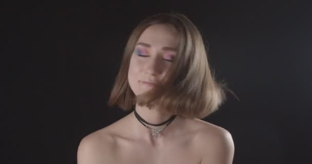 Closeup lő a fiatal aranyos kaukázusi rövid hajú nő aranyos smink feldobás haját nézi kamera háttérrel izolált fekete — Stock videók