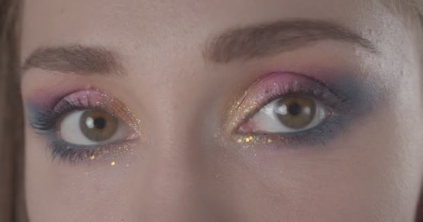 Closeup shoot of young cute caucasian short haired female face with glitter makeup looking at camera with background isolated on black — Stock Video