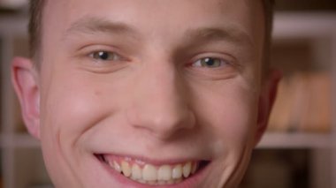 Üniversite kütüphanesinde kameraya bakan genç kendine güvenen beyaz erkek öğrencinin yakın çekim çekimi