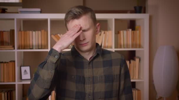 Närbild shoot av unga attraktiva kaukasiska manliga studenten gör ett ansikte Palm är irriterad tittar på kameran i kollegiet biblioteket — Stockvideo