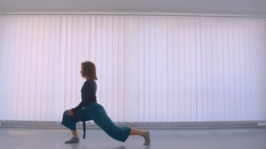 Genç güzel esnek kadın düz bir kapalı boş odada duygusal bir dans performans Motion shoot