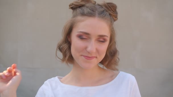 Nahaufnahme einer jungen niedlichen kaukasischen Frau mit Haarsträhnen, die glücklich lächelnd in die Kamera blickt und im Hintergrund die Stadt zeigt — Stockvideo