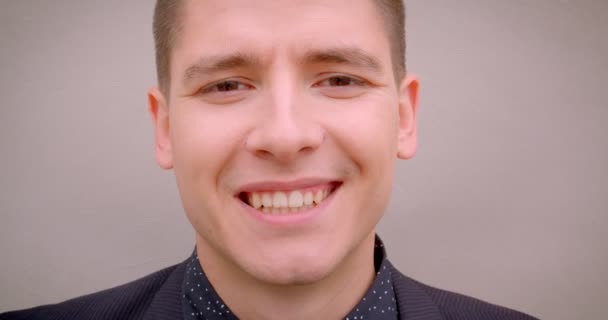 Closeup hajtás a fiatal vidám kaukázusi szőke férfi mosolyogva boldogan nézi a kamerát a fal a háttérben — Stock videók