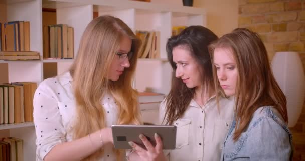Sesión de primer plano de joven hermosa pareja lesbiana hablando con agente inmobiliario femenino con tableta sobre la compra de un apartamento — Vídeo de stock