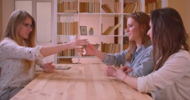 Genç güzel lezbiyen çift in Closeup yan görünüm ateş bir daire satın alma hakkında kadın emlakçı konuşurken anahtarları kapalı masanın yanında oturan alma